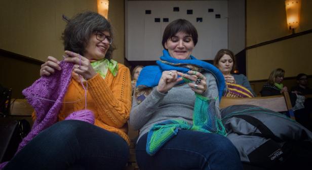 Frauen sitzen in einer Gruppe und stricken an ihren Strickprojekten.