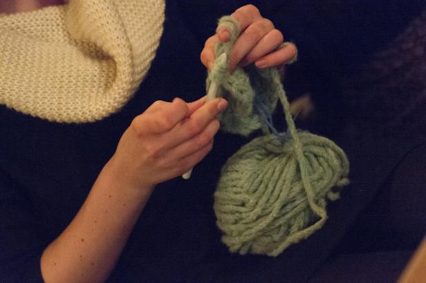 Eine Person häkelt mit hellgrüner Wolle.