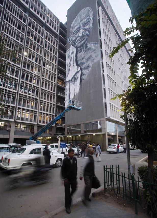 Ein großes Wandgemälde von Mahatma Gandhi an einem Gebäude in Indien.