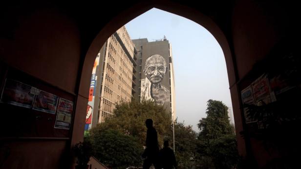 Ein großes Wandgemälde von Mahatma Gandhi an einem Gebäude in Indien.