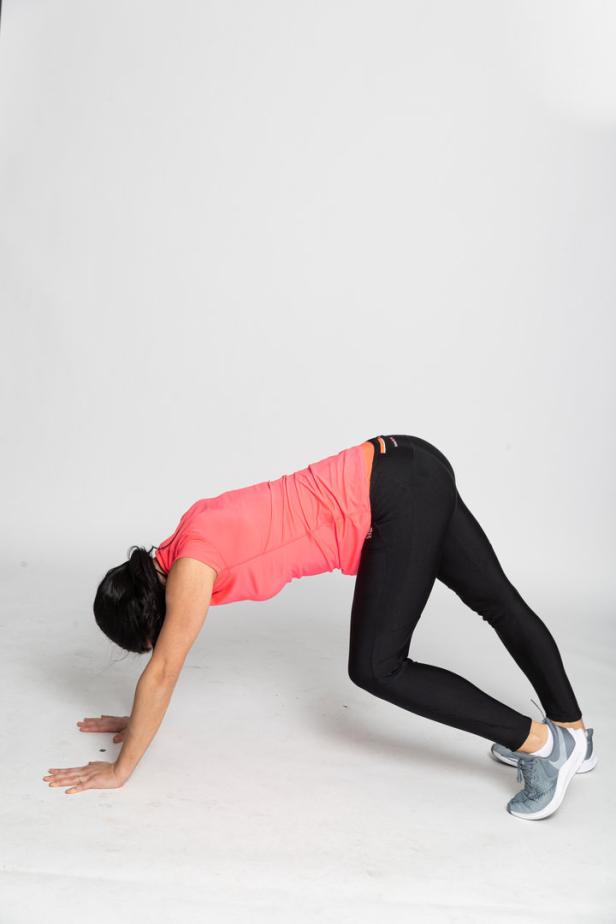 Eine Frau macht Yoga in einer herabschauenden Hundeposition.