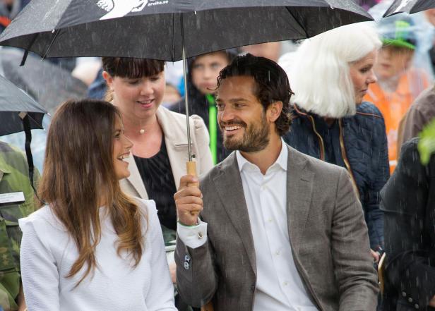 Prinz Carl Philip und Prinzessin Sofia unter einem Regenschirm bei einer Veranstaltung.