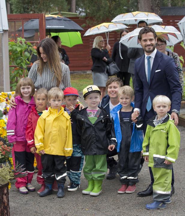 Prinz Carl Philip und Prinzessin Sofia mit einer Gruppe von Kindern im Regen.