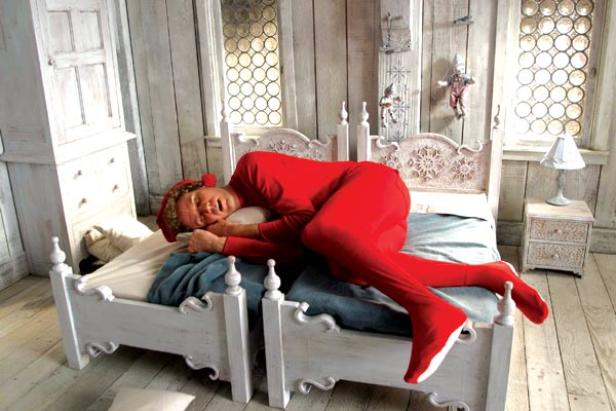 Ein Mann im roten Schlafanzug liegt schlafend in einem weißen Bett.