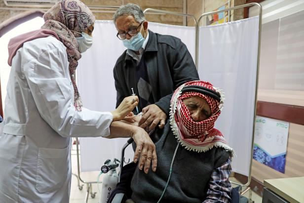 FILE PHOTO: A Palestinian man is helped by his son as he receives a vaccination against the coronavirus disease (COVID-19) as Israel continues its national vaccination drive, in East Jerusalem
