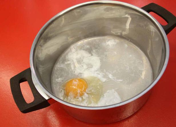 Ein pochiertes Ei schwimmt in einem Topf mit heißem Wasser.
