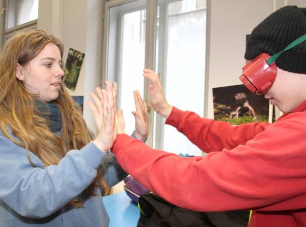 Eine junge Frau spielt mit einem Jungen, der eine Simulationsbrille trägt.