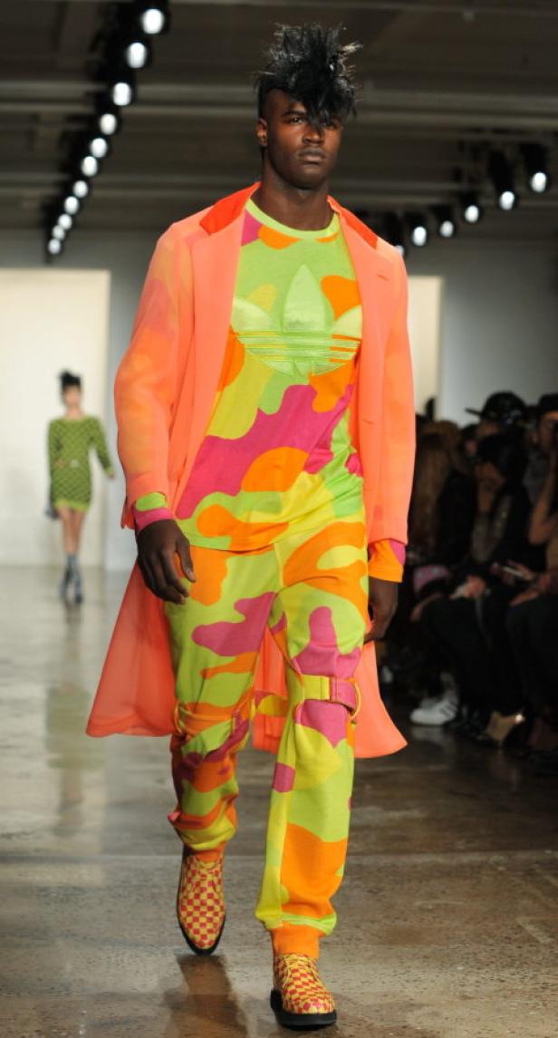 Ein Mann mit Irokesenschnitt präsentiert farbenfrohe Mode auf einem Laufsteg.