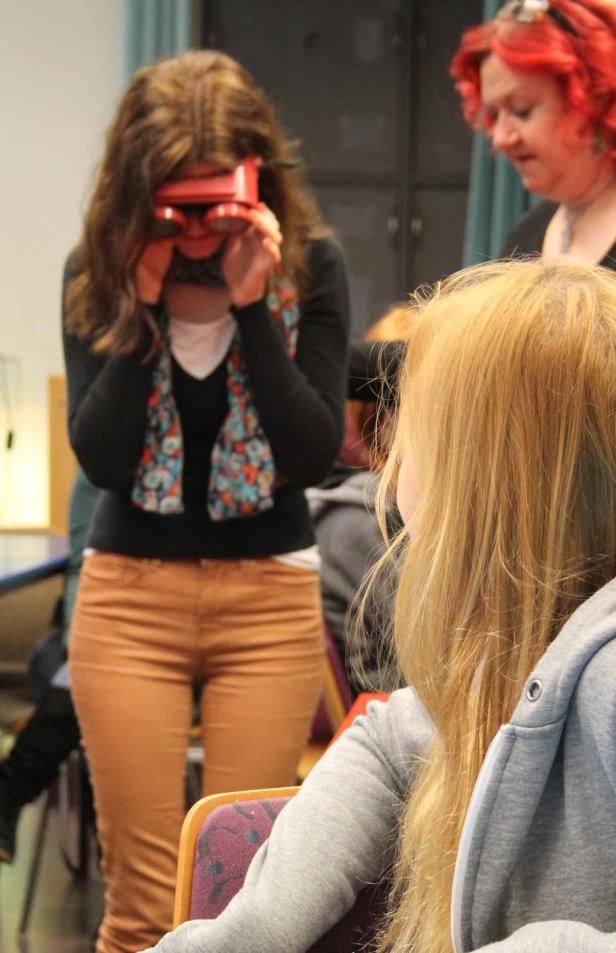 Eine Frau blickt durch ein rotes Stereoskop.