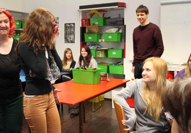 Eine Gruppe von Studenten in einem Klassenzimmer mit einem orangefarbenen Tisch.