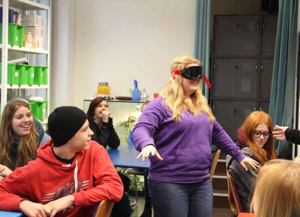 Eine junge Frau mit Skibrille steht vor einer Gruppe von Jugendlichen.