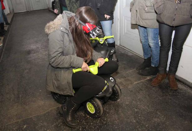 Eine Frau mit roter Brille fährt auf einem schwarzen Rutschauto.