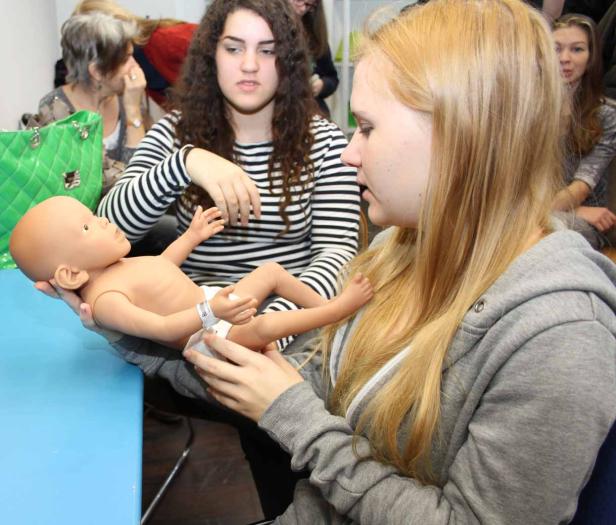 Zwei junge Frauen halten eine Babypuppe in einem Kurs oder einer Übung.