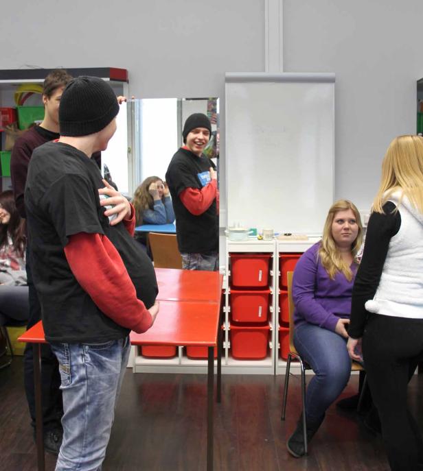 Eine Gruppe junger Leute steht und sitzt in einem Raum.