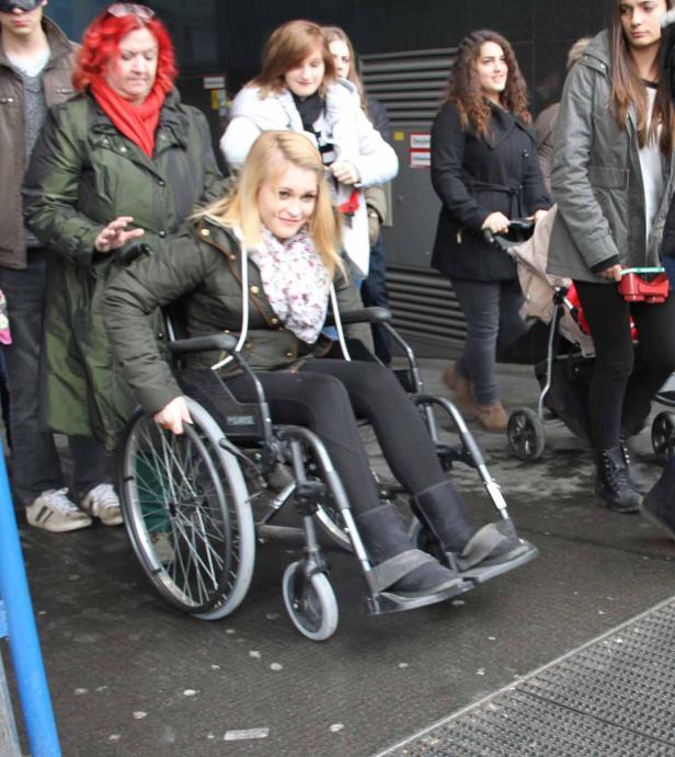 Eine junge Frau im Rollstuhl wird von einer anderen Frau geschoben.