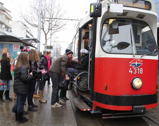 Eine Person im Rollstuhl wird in Wien in eine Straßenbahn der Linie „Börsegasse“ gehoben.