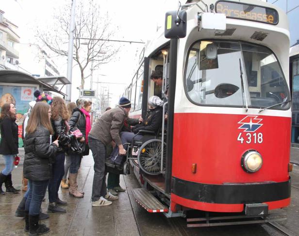 Eine Person im Rollstuhl wird in eine Straßenbahn in Wien geschoben.
