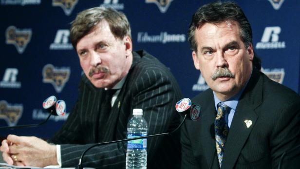 Zwei Männer in Anzügen sitzen vor einem Hintergrund mit dem Logo der Los Angeles Rams.