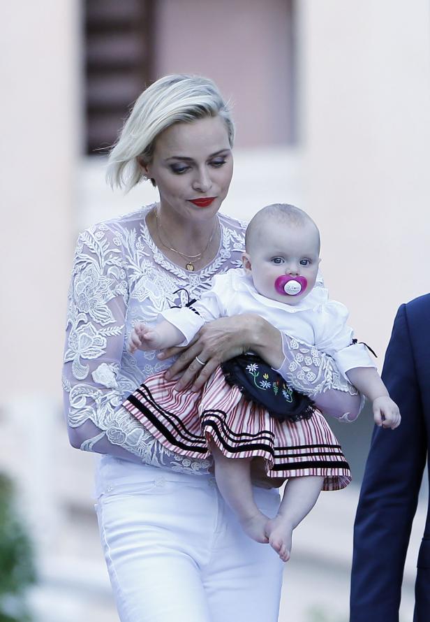 Fürstin Charlène hält ein Baby mit Schnuller im Arm.