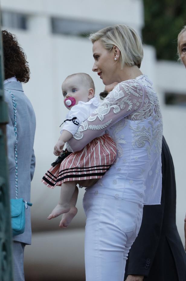 Fürstin Charlène hält ein Baby mit Schnuller im Arm.