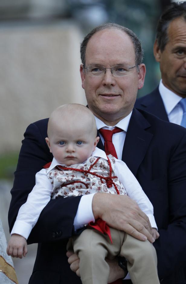 Fürst Albert II. von Monaco hält ein Baby im Arm.