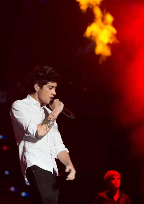 Zayn Malik singt während eines Konzerts mit Flammeneffekten im Hintergrund.