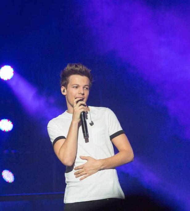 Louis Tomlinson singt während eines Konzerts in ein Mikrofon.