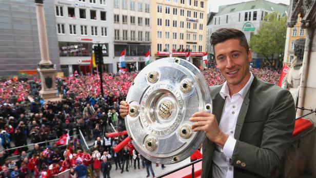 Robert Lewandowski präsentiert die Meisterschale des FC Bayern München vor einer jubelnden Menschenmenge.