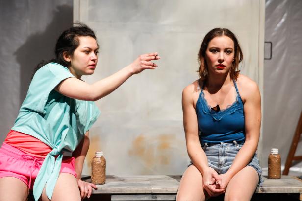 Zwei Schauspielerinnen als jugendliche Mädchen sitzen auf einer Holzbank