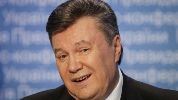 Ein Porträt von Viktor Janukowytsch vor einem blauen Hintergrund.