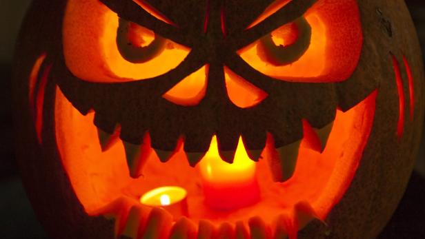 Ein gruseliger Halloween-Kürbis mit Kerzenlicht im Inneren.