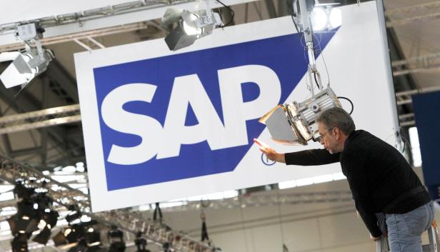 Ein Mann justiert die Beleuchtung vor einem großen SAP-Logo.