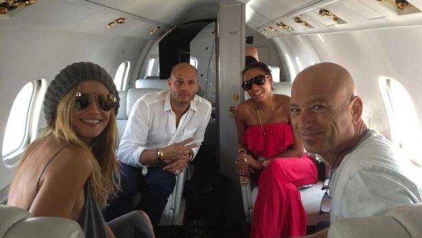 Vier Personen sitzen in einem Privatjet und lächeln in die Kamera.