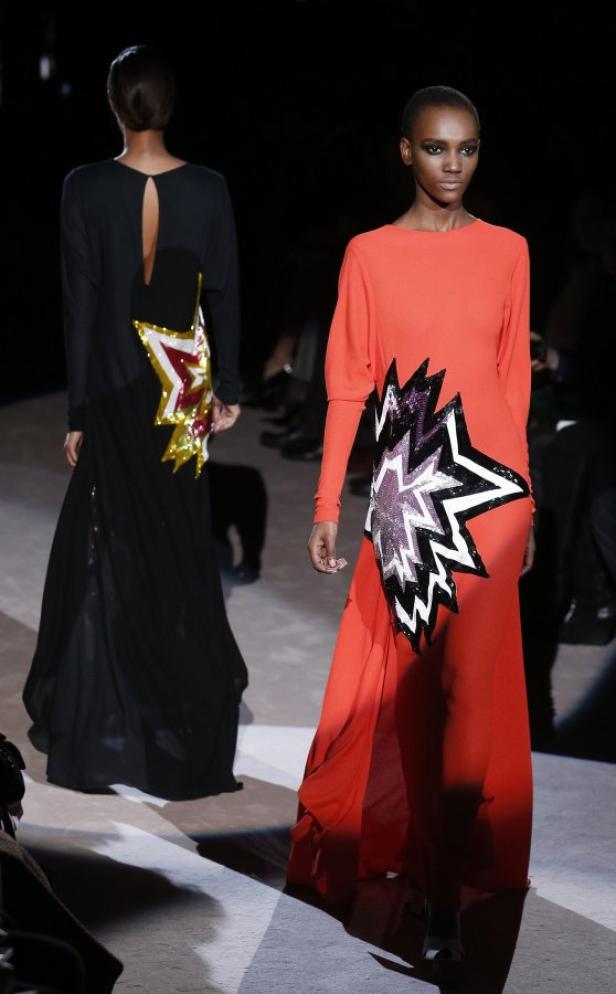 Zwei Models präsentieren lange Kleider mit Sternapplikationen auf einem Laufsteg.