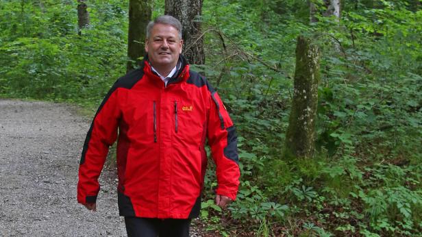 Andrä Rupprechter Ein Mann in einer roten Jack Wolfskin Jacke geht auf einem Waldweg.
