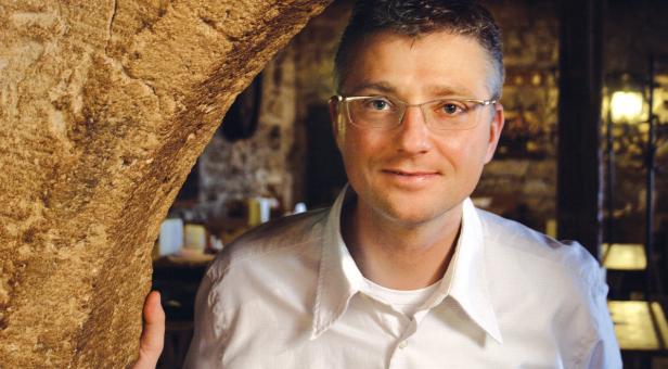 Ein Mann mit Brille lehnt an einer steinernen Säule.