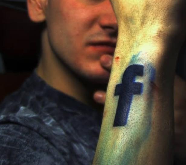 Ein Mann mit einem Tattoo des Facebook-Logos auf seinem Unterarm.