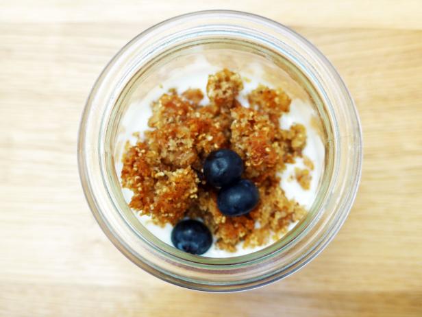 Ein Glas mit Joghurt, Müsli und Blaubeeren von oben betrachtet.