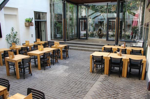 Ein Innenhof mit Tischen und Stühlen vor einem verglasten Gebäude.