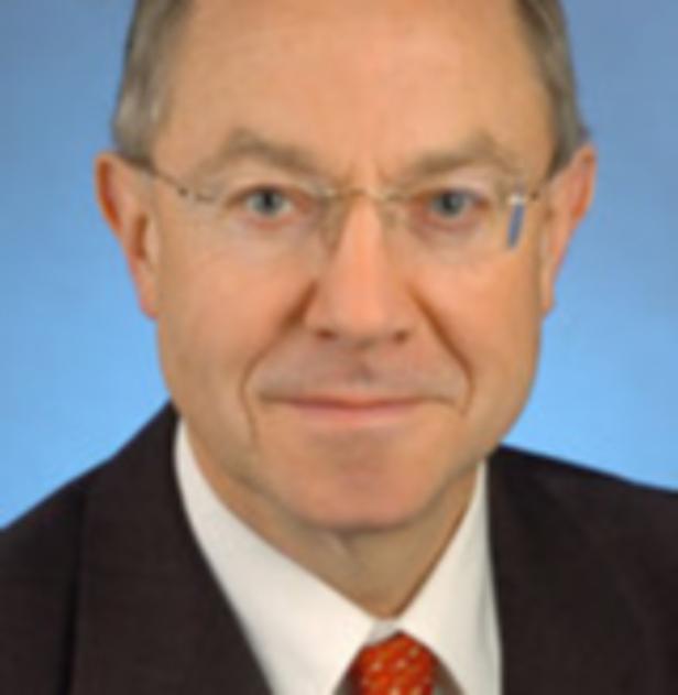 Magistrat Salzburg Leiter Soziales Winfried Wagner… Ein Porträt eines Mannes mit Brille, Anzug und Krawatte vor blauem Hintergrund.