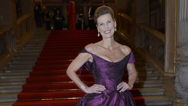 Eine Frau in einem lila Kleid posiert auf einer roten Treppe.