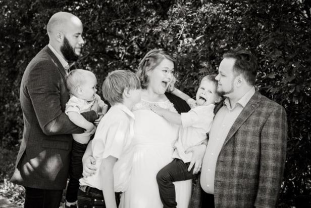 Eine Familie posiert für ein Schwarzweißfoto, wobei die Kinder unterschiedliche Gesichtsausdrücke zeigen.