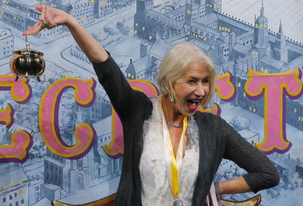 Helen Mirren hält einen goldenen Topf in die Höhe und lacht.