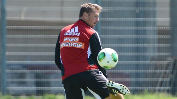 Ein Mann in Sportkleidung jongliert mit einem Fußball.