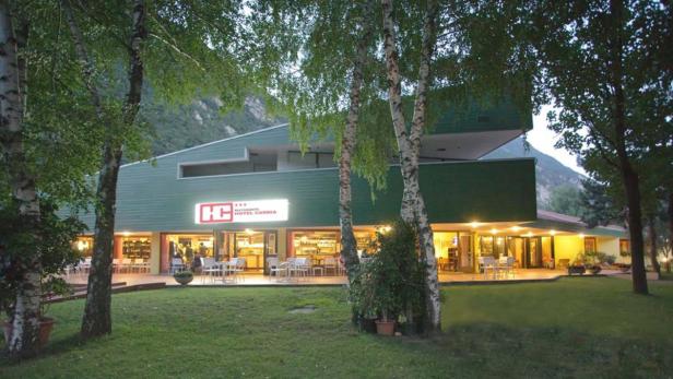 Das Hotel Carnia mit Restaurant liegt in einer grünen Landschaft.