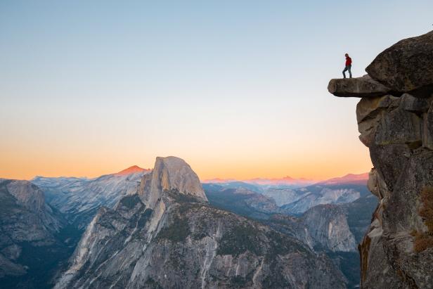 Eine Person steht auf einem Felsvorsprung mit Blick auf das Yosemite Valley.