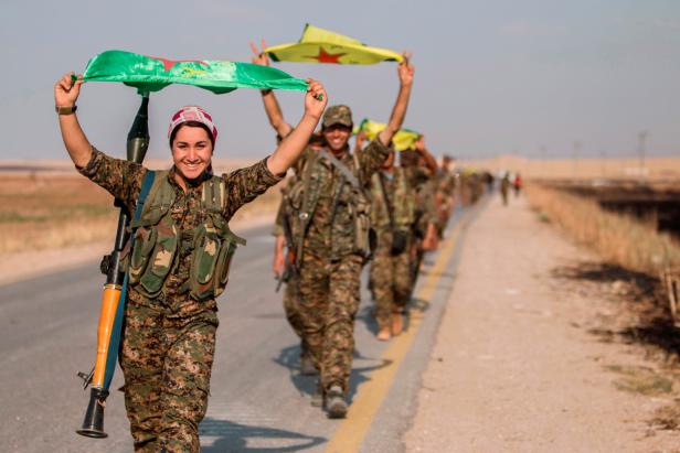 FILE PHOTO: Kurdish fighters gesture while carrying their parties' flags in Tel Abyad of Raqqa governorate after they said they took control of the area