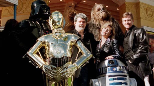 George Lucas, Mark Hamill, Carrie Fisher und Star Wars-Charaktere posieren für ein Foto.