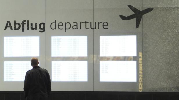 Ein Mann steht vor einer Anzeigetafel mit Flugplänen am Flughafen.
