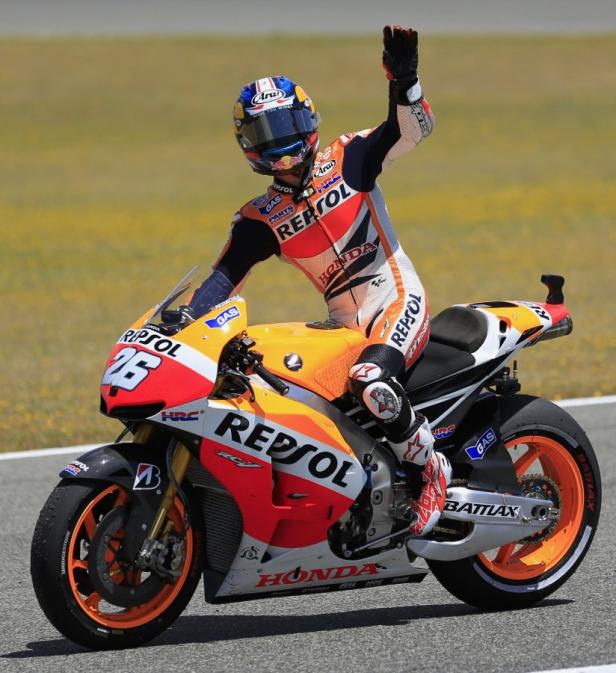 Ein Rennfahrer auf einem Repsol Honda Motorrad winkt dem Publikum zu.